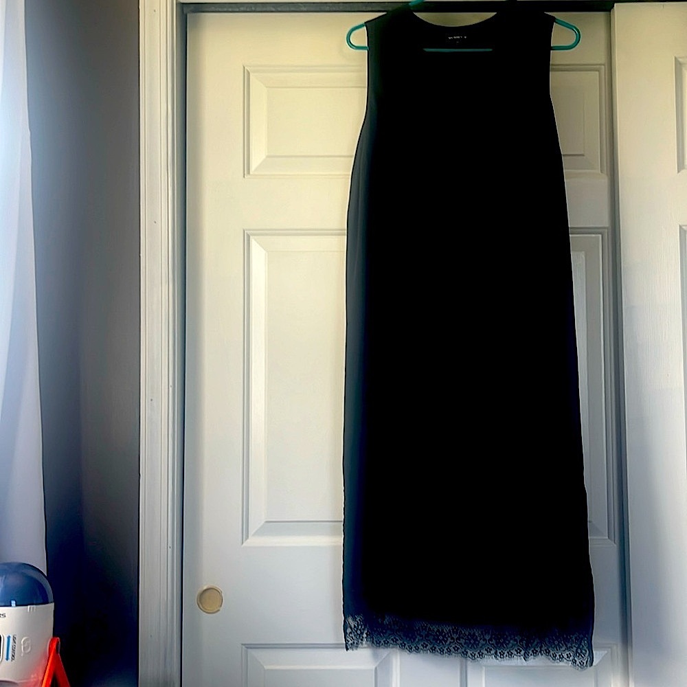 Black knee length sleeveless dress with lace trim.